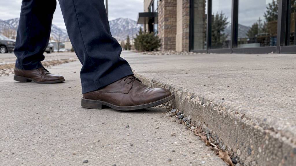 Raised sidewalk edge beside a passerby’s shoe